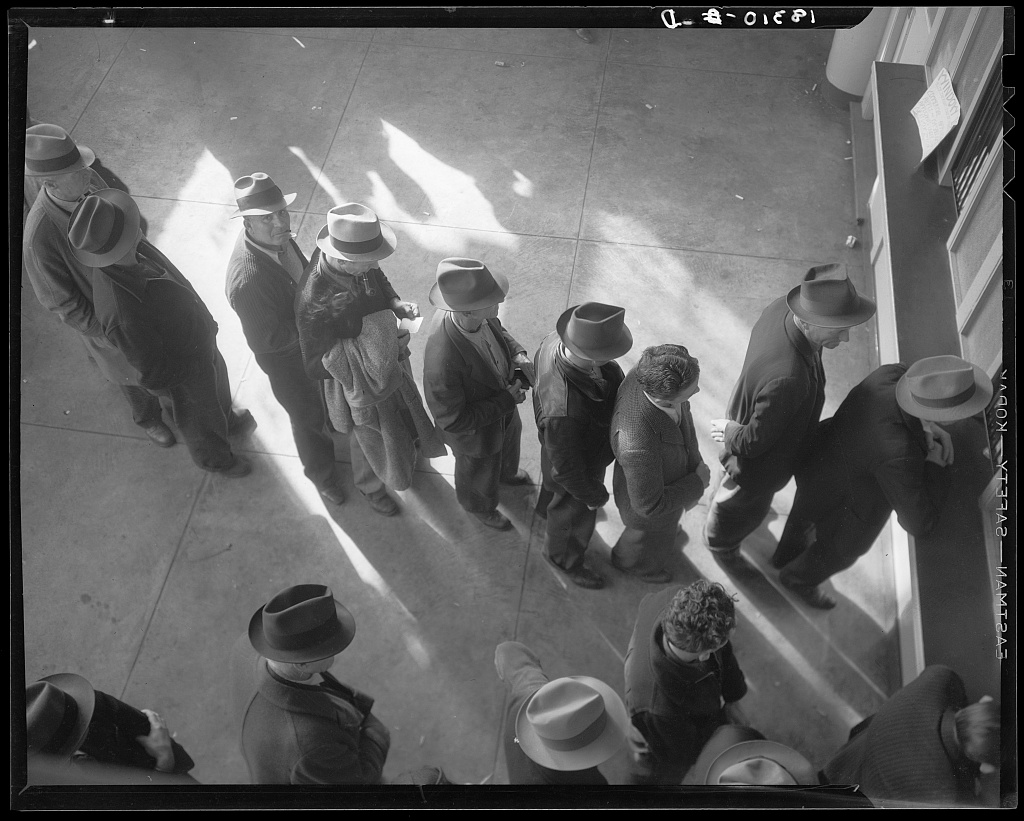 Men stand in a curving line inside a San Francisco employment-service office to register for unemployment benefits.
