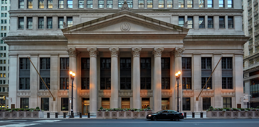 The Federal Reserve Bank of Chicago's columned stone facade fills the block, with the bank's seal above the entrance.